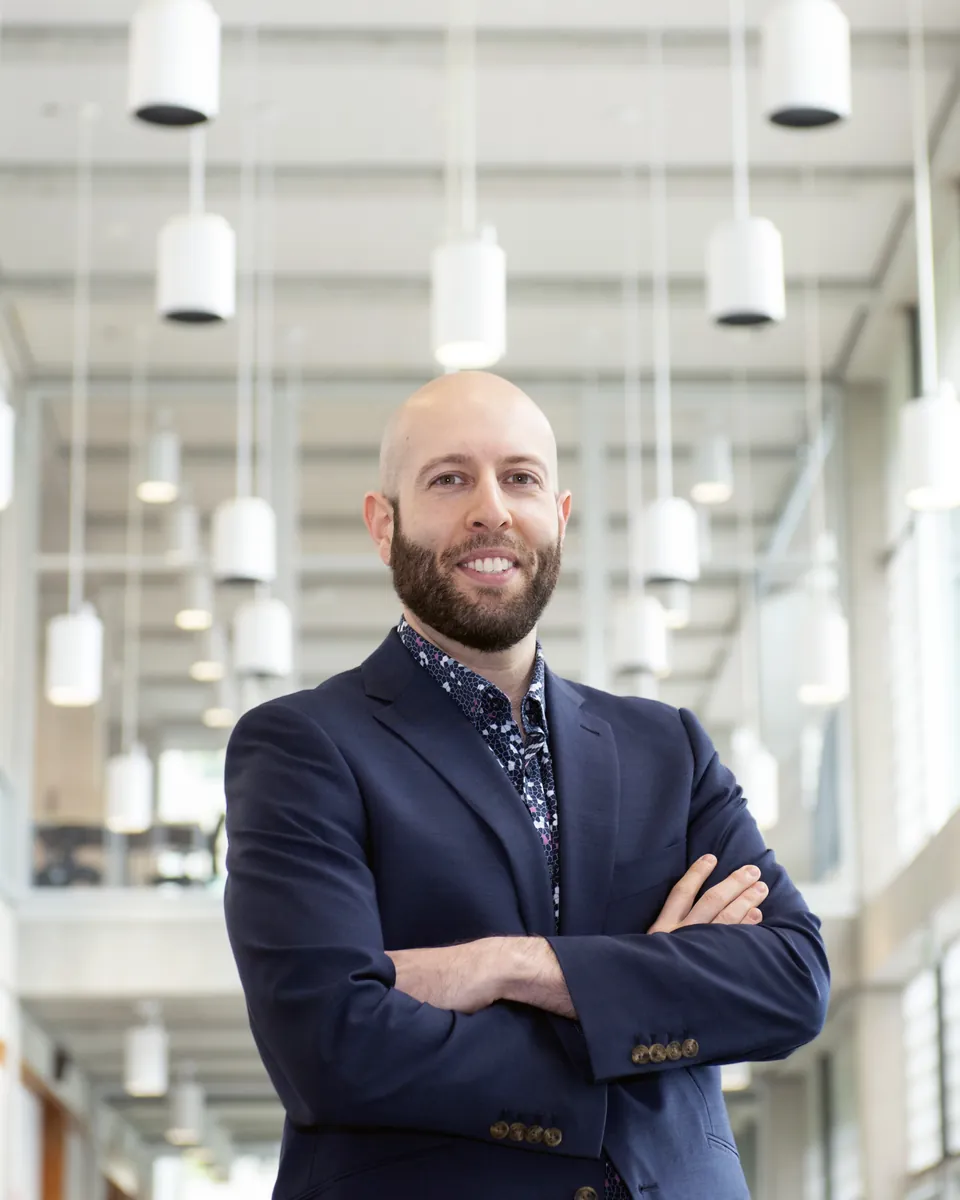 Dr. Aryan Sarparast standing with arms crossed in a bright atrium
