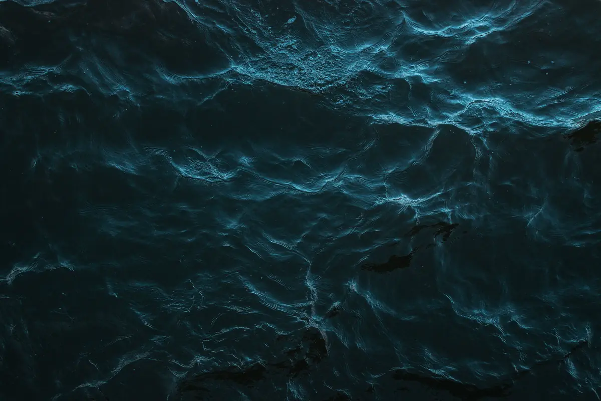 Dark ocean water seen from above, with blue light catching the waves